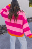 Woman from behind in a pink striped knit sweater with orange trim and light gray pants outdoors.