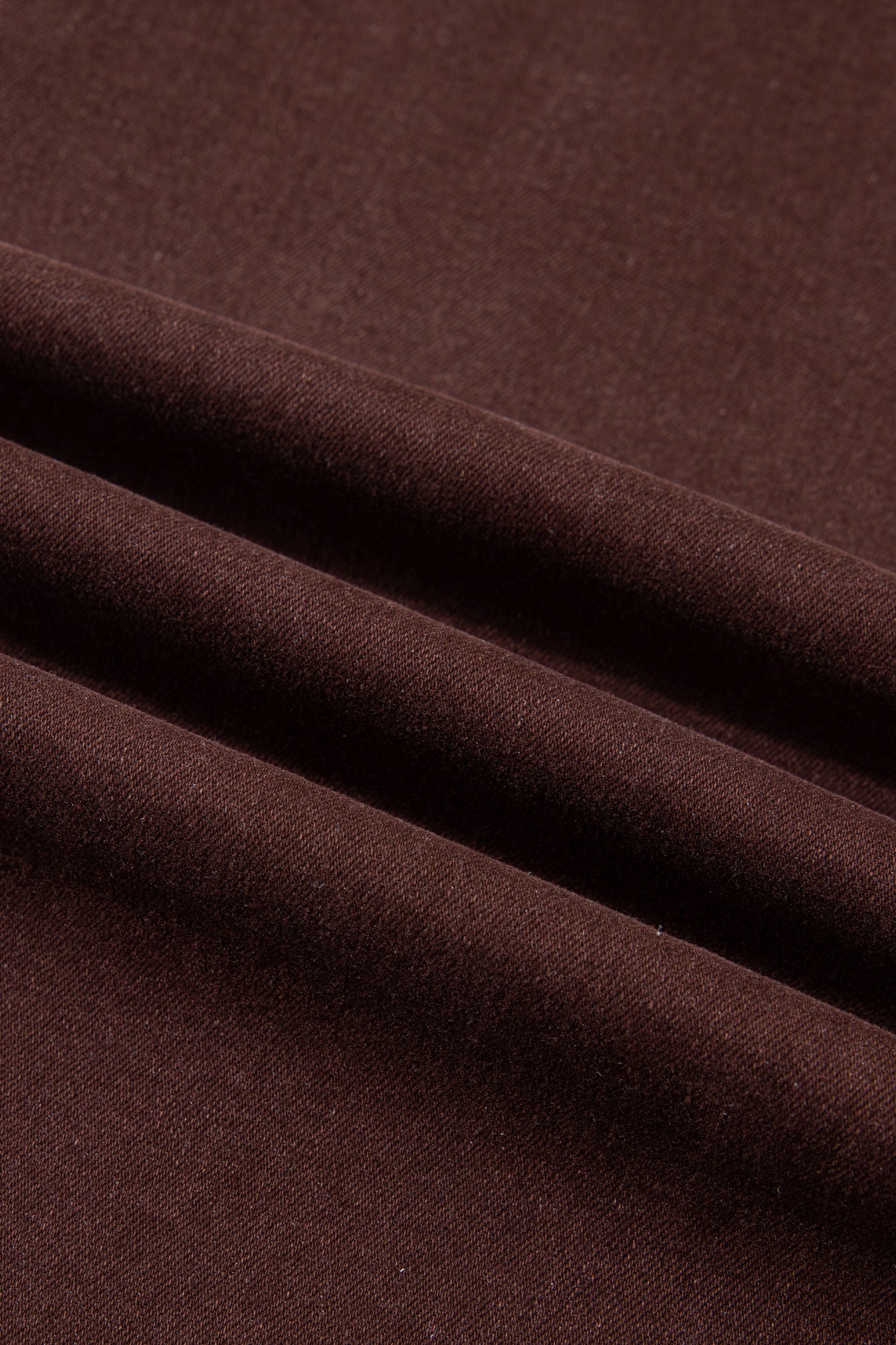 A close-up of draped dark brown fabric with soft folds showing its texture and color.