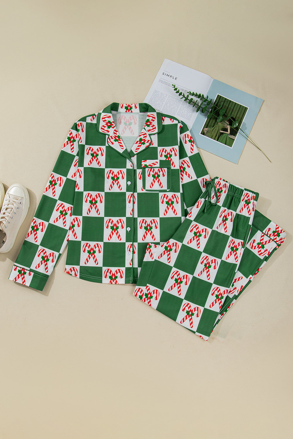 Green and red checkered pajama set on a beige surface with a book and plant.