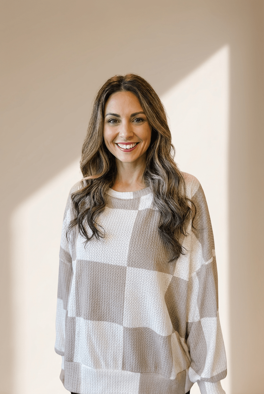 Woman wearing a checkered sweater standing against a neutral background
