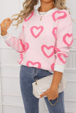 Person wearing a pink sweater with heart patterns, holding a white clutch.