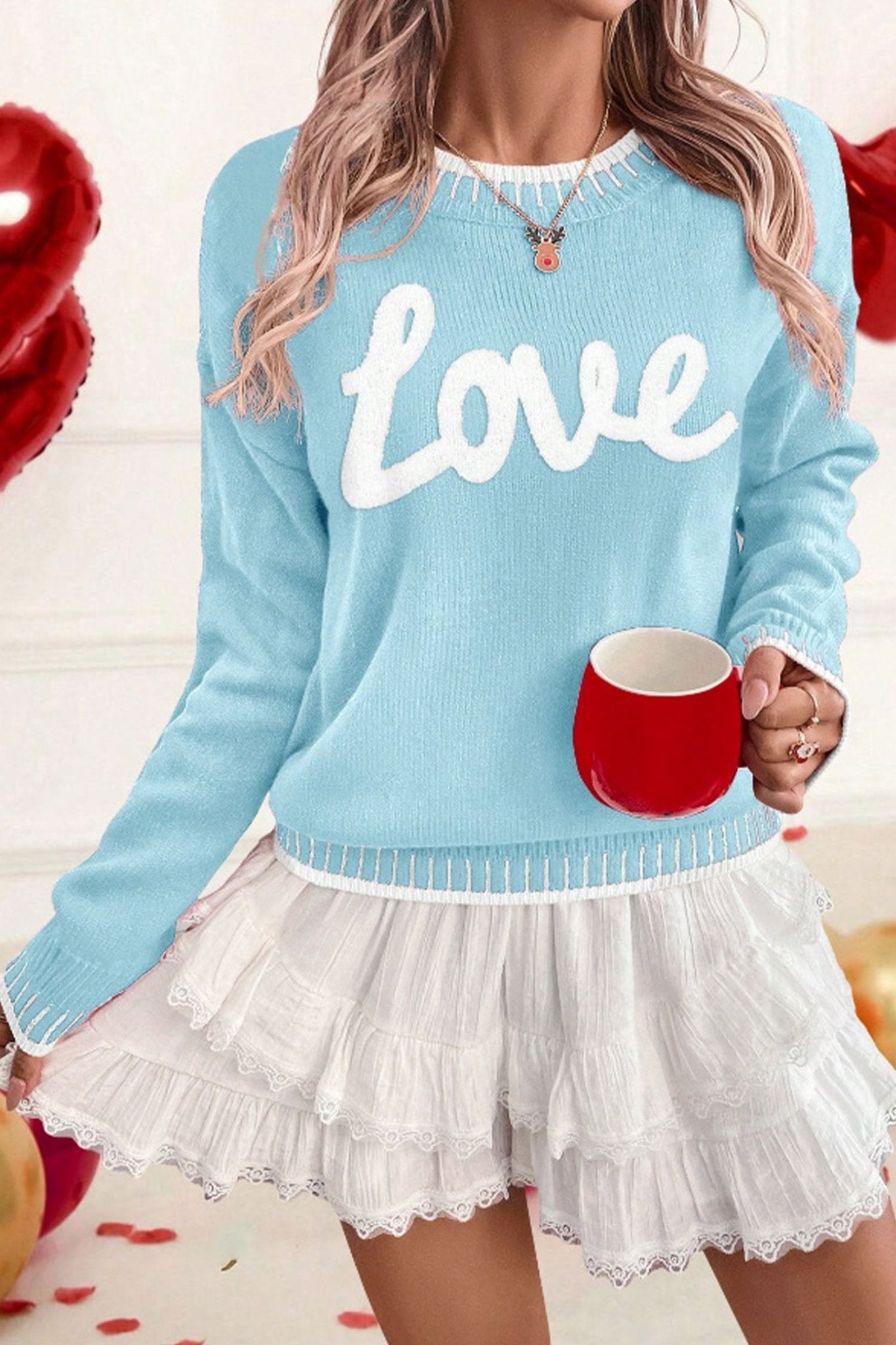Person wearing a light blue sweater with 'LOVE' text, holding a red mug, on a white background.