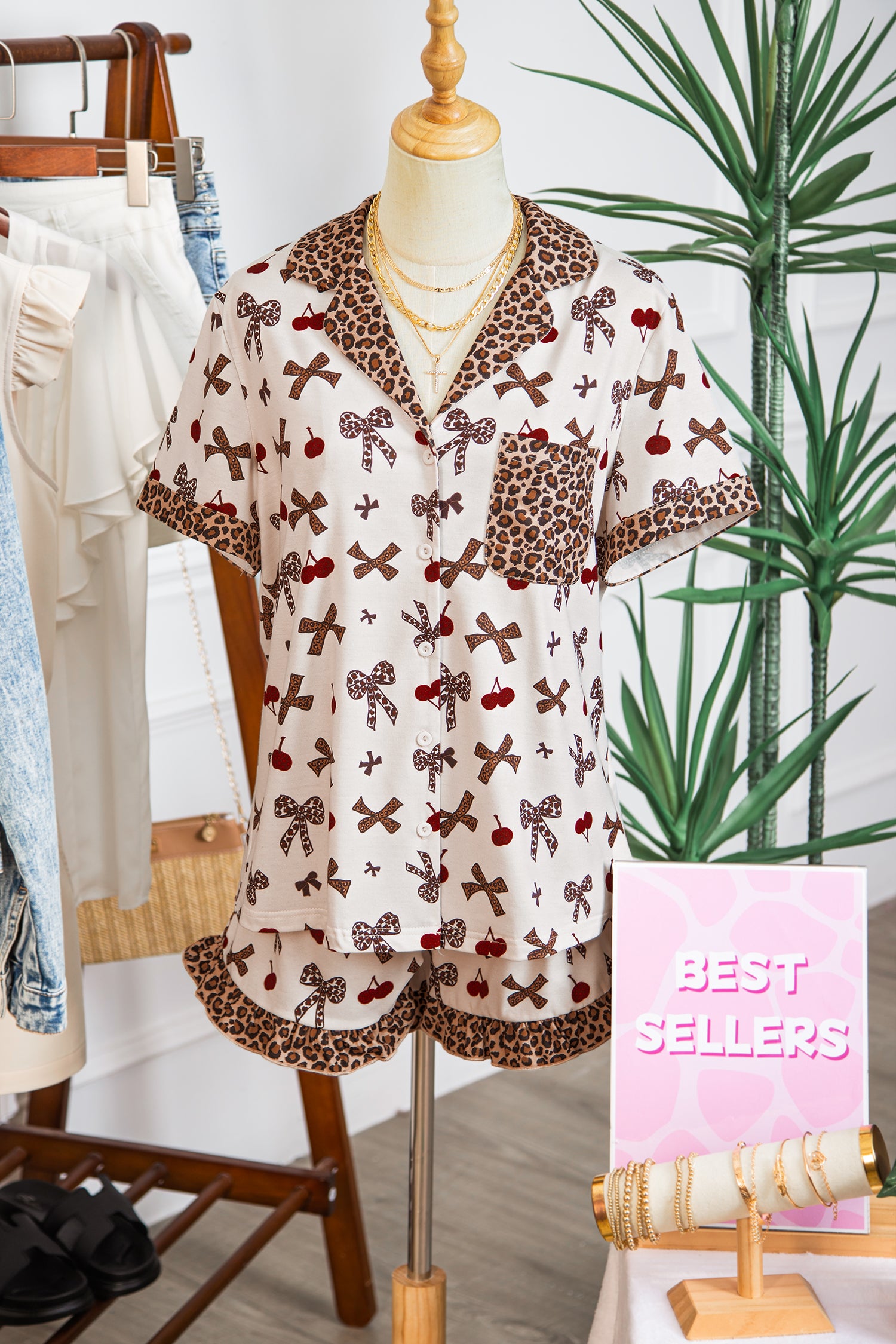 Mannequin wearing a patterned blouse with bows and cherries in a store setting.