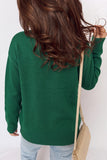 Back view of woman in green knit sweater, light blue jeans, and beige shoulder bag.