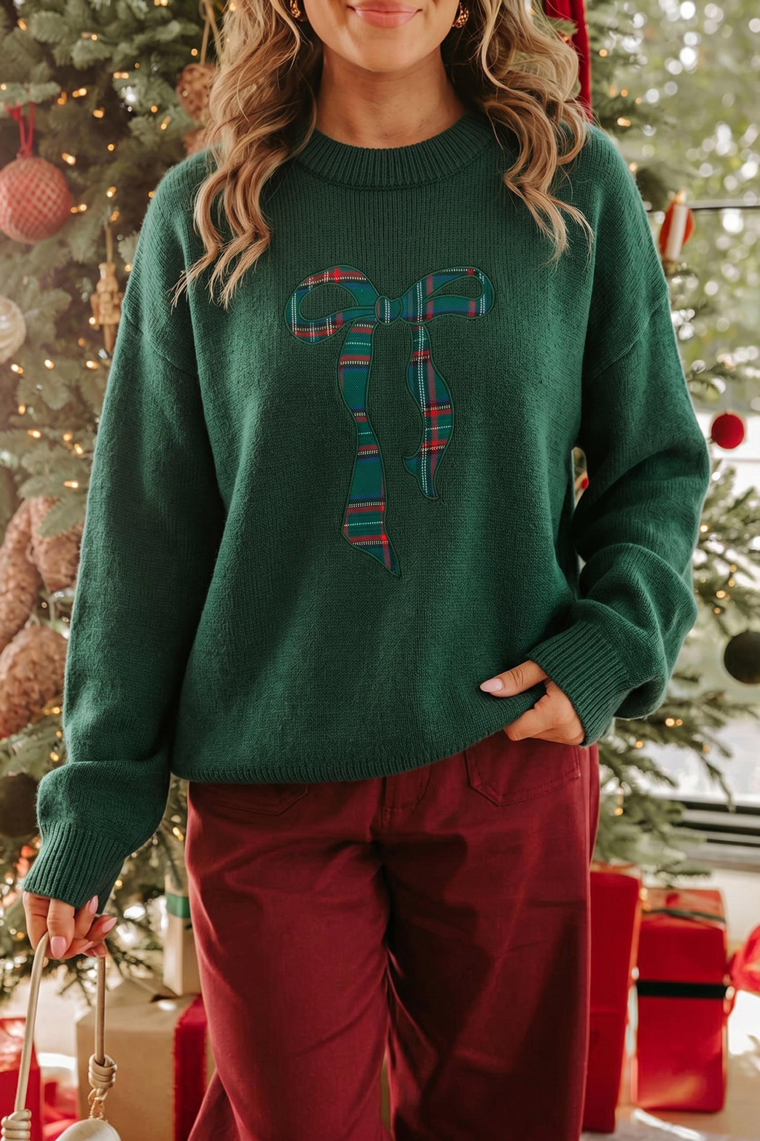 Woman in dark green sweater with plaid candy cane graphic and burgundy pants.