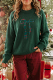 Woman in dark green sweater with plaid candy cane graphic and burgundy pants.