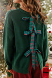 Woman in dark green knit sweater with large plaid ribbon on back.