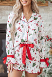 Woman wearing white Christmas-print pajamas with red waist tie and cuffs.