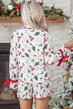 Woman viewed from behind in white Christmas-print pajamas by a decorated tree.