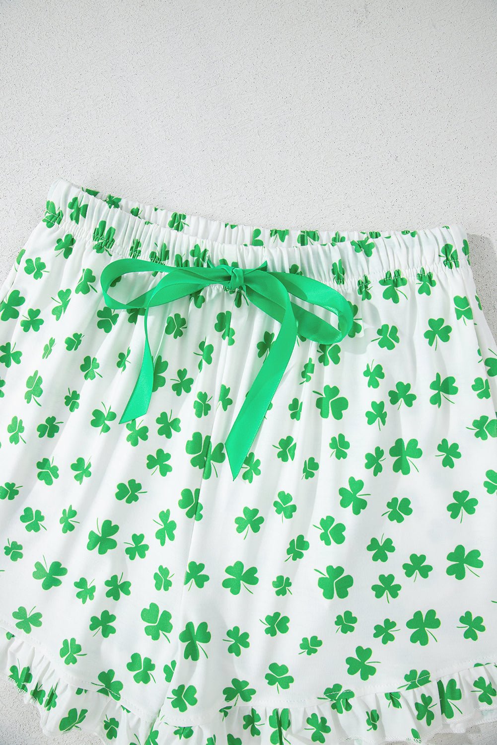 Green shamrock-patterned shorts with a green ribbon on a white background