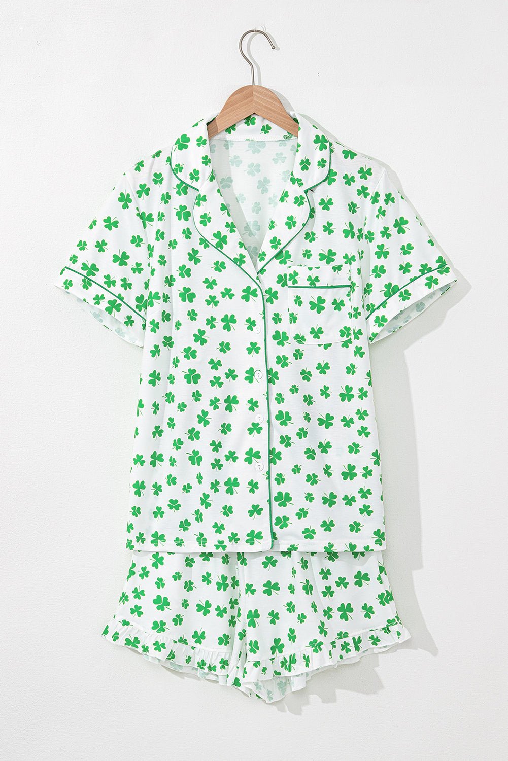 Green shamrock patterned pajama set on a hanger against a white background