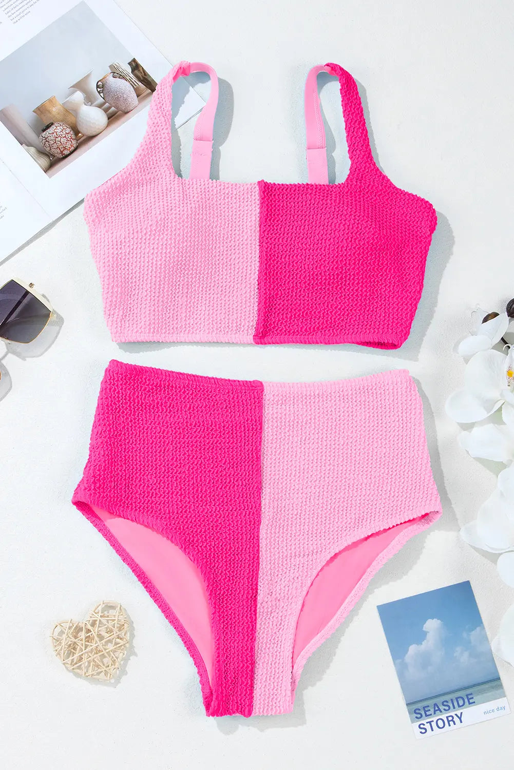 Pink two-piece swimsuit on a white background with decorative items.