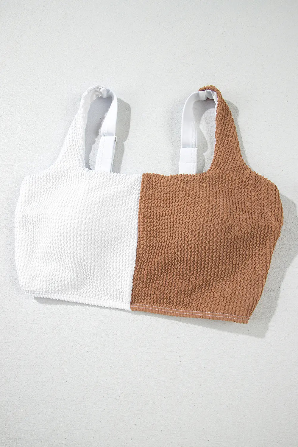 Two knit tops, one white and one brown, on a light gray background.