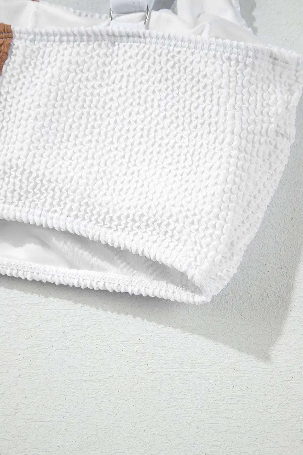 Close-up of a textured white fabric with a soft shadow on a light gray background