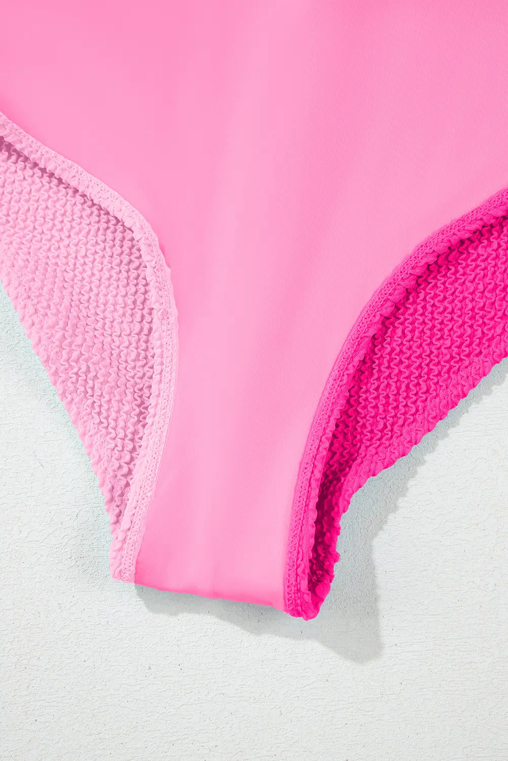 Close-up of pink bikini bottom with textured edges on a light gray background