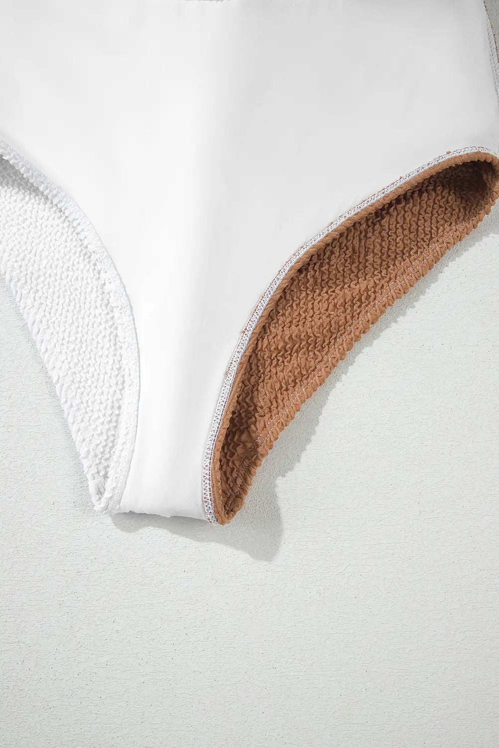 Close-up of a white bra with brown trim on a light gray background