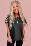 Woman wearing a dark green t-shirt with leopard print sleeves on a pink background
