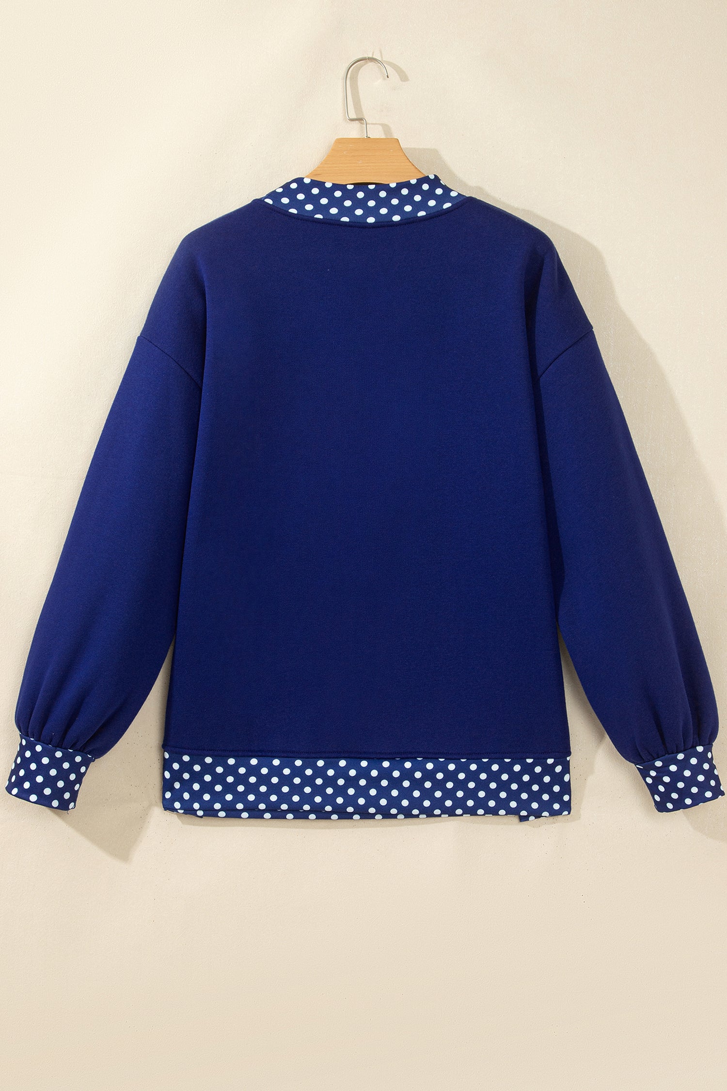 Royal blue sweatshirt with white polka-dot trim at collar, cuffs, and hem.