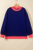 Navy blue sweater with red-white polka-dot trim on wooden hang.