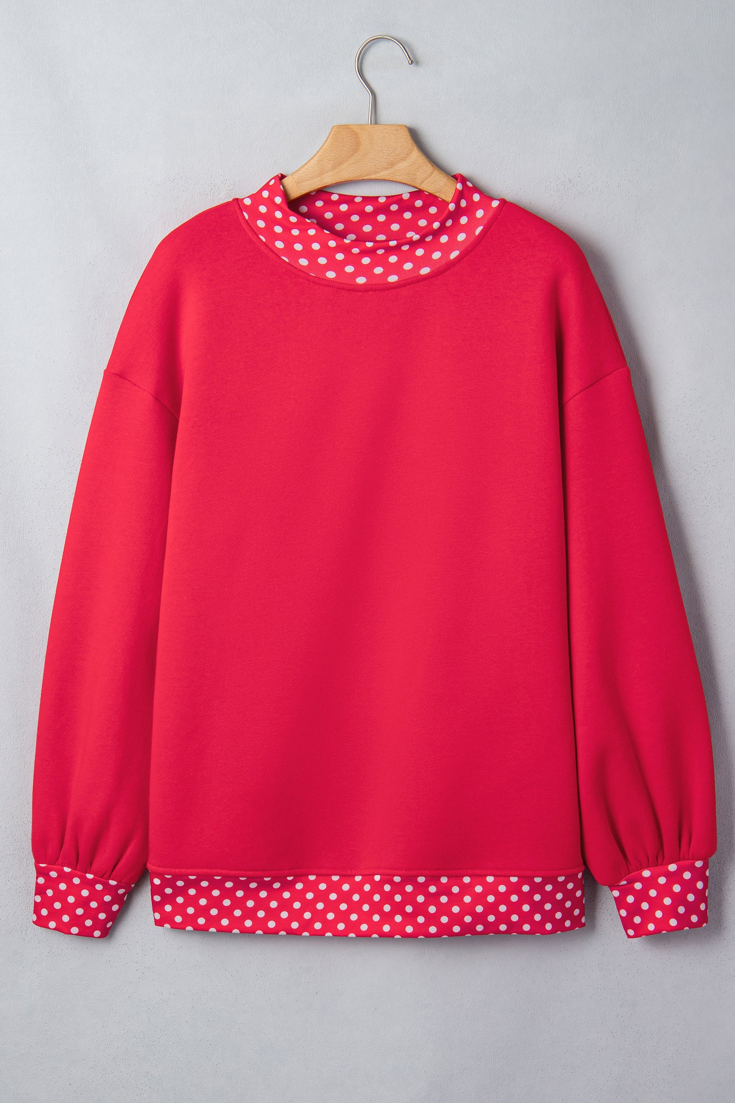 Bright red sweatshirt with white polka-dot trim on mock neck, cuffs, and hem.