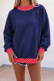 Woman in oversized navy sweatshirt with red-white polka-dot trim and denim short.
