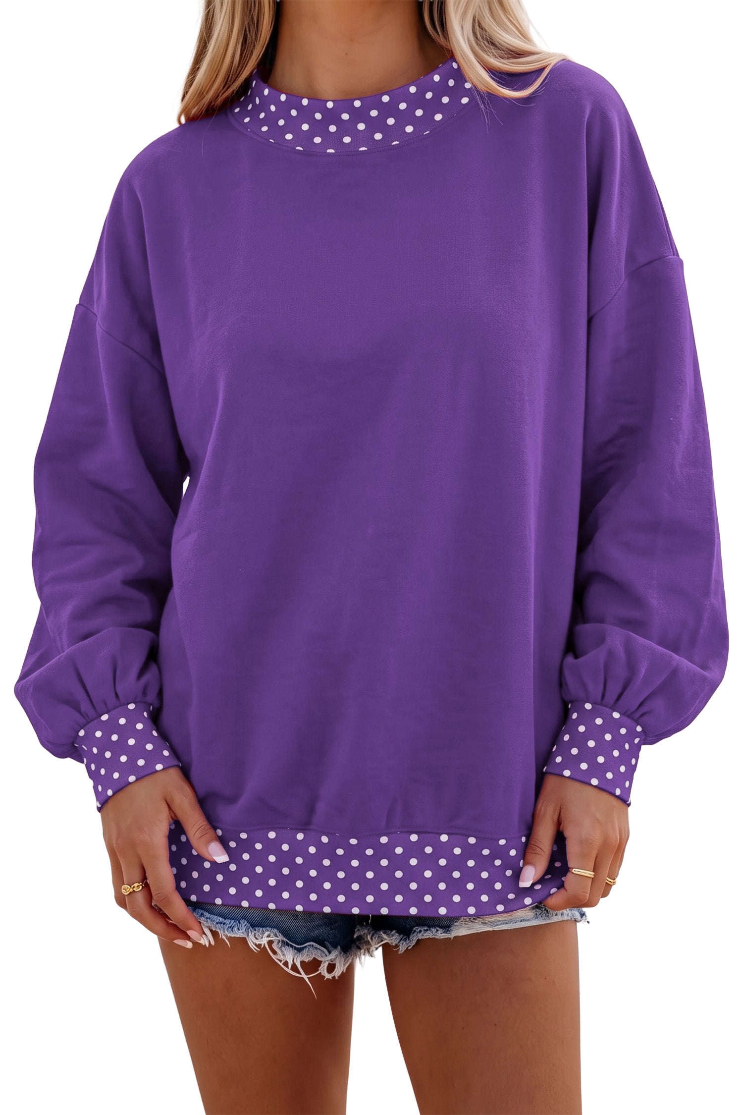 A woman wearing a purple crewneck sweatshirt with white polka dot trim background.