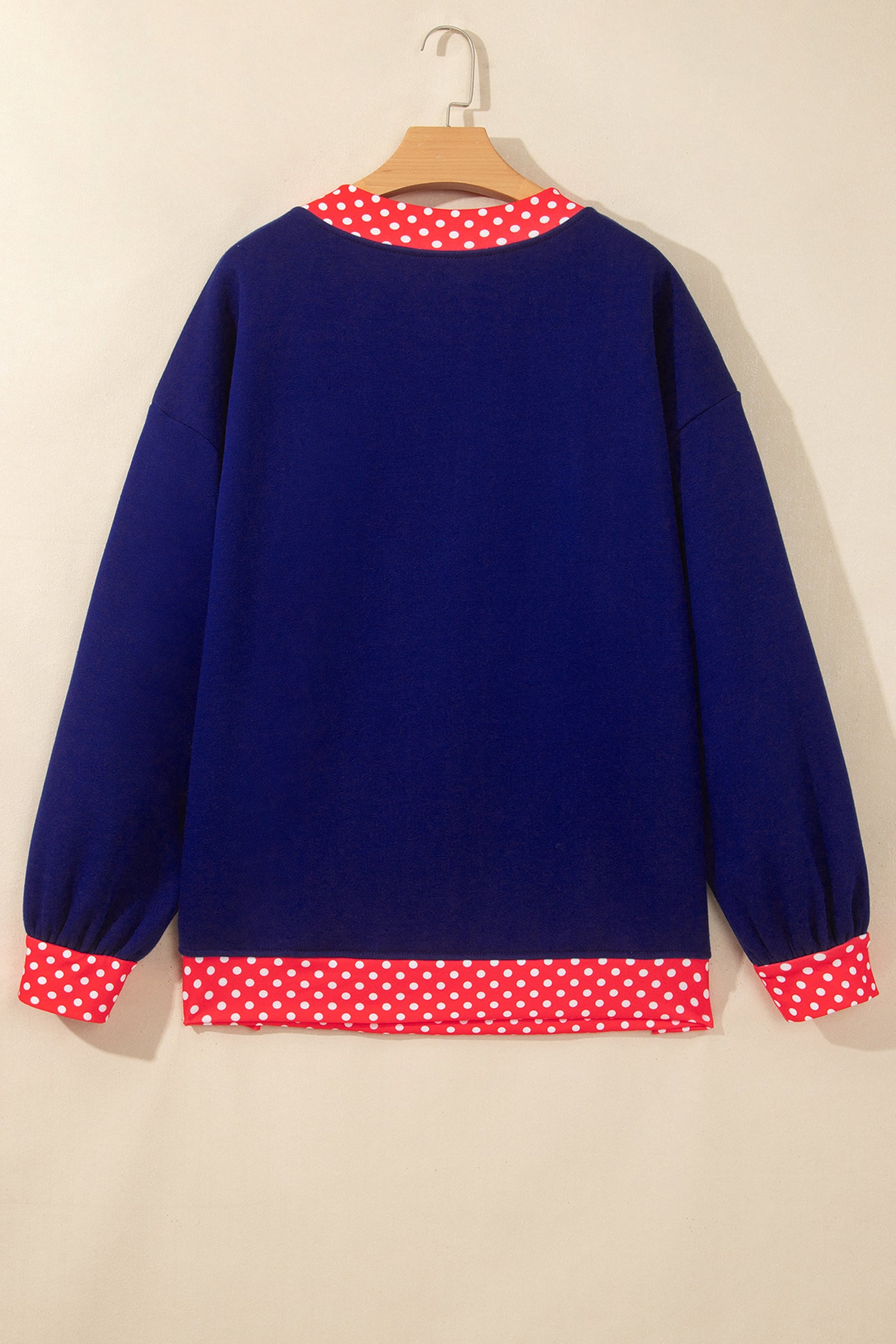 Navy blue sweater with red-white polka-dot trim at collar, cuffs, and hem.