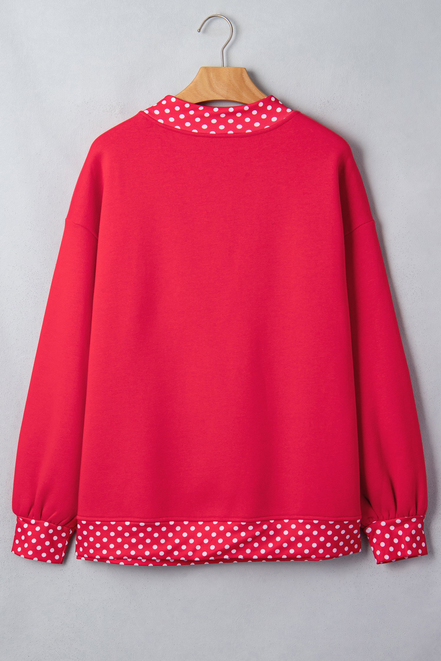Bright red sweatshirt with white polka-dot trim on collar and cuffs.