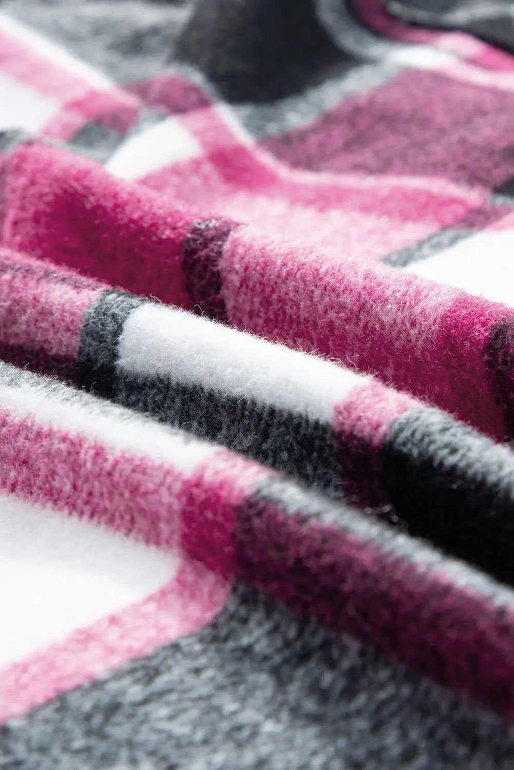 A close-up of a soft, plush fabric with a plaid pattern in pink, white, and dark gray.