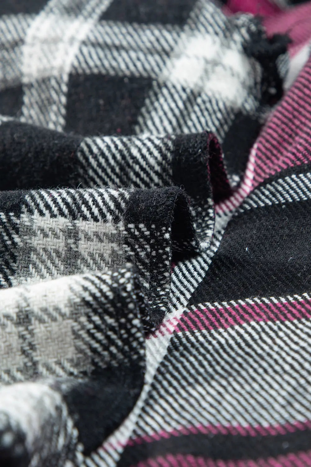 Close-up of plaid fabric with black, white, and pink colors.