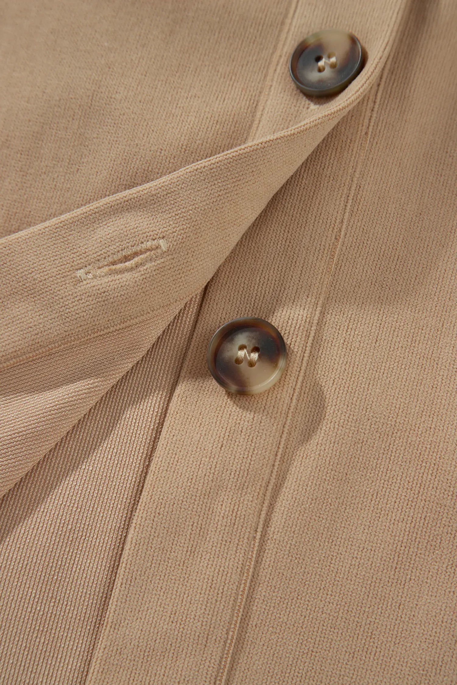 Close-up of a beige textured fabric garment with two dark brown buttons on a button placket.