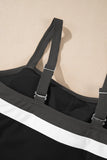 Close-up of a black swimsuit or tank top with wide adjustable shoulder straps and a bold white horizontal stripe across the front, shown against a warm beige background.