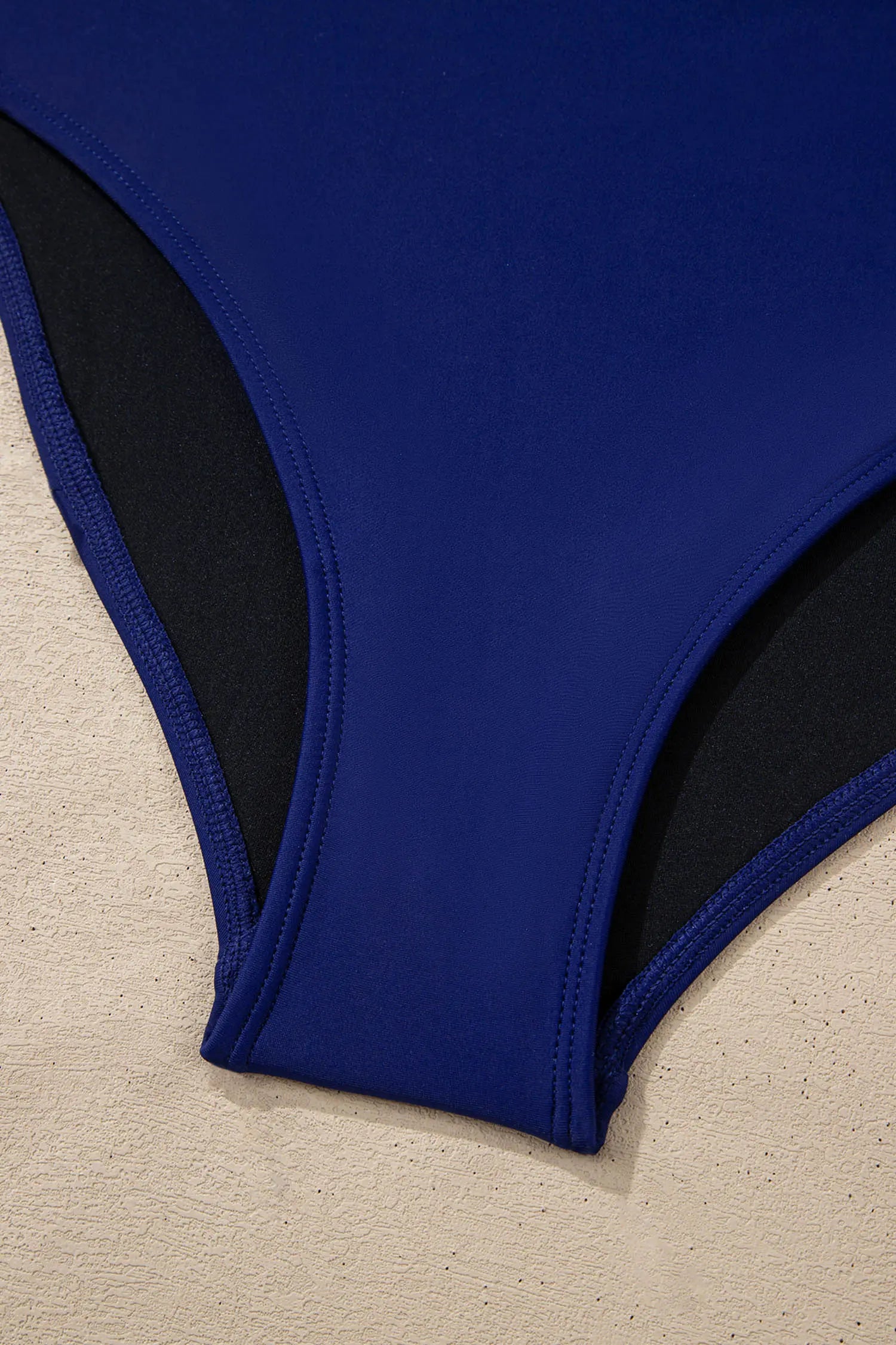 Blue swimsuit with black lining on a beige surface