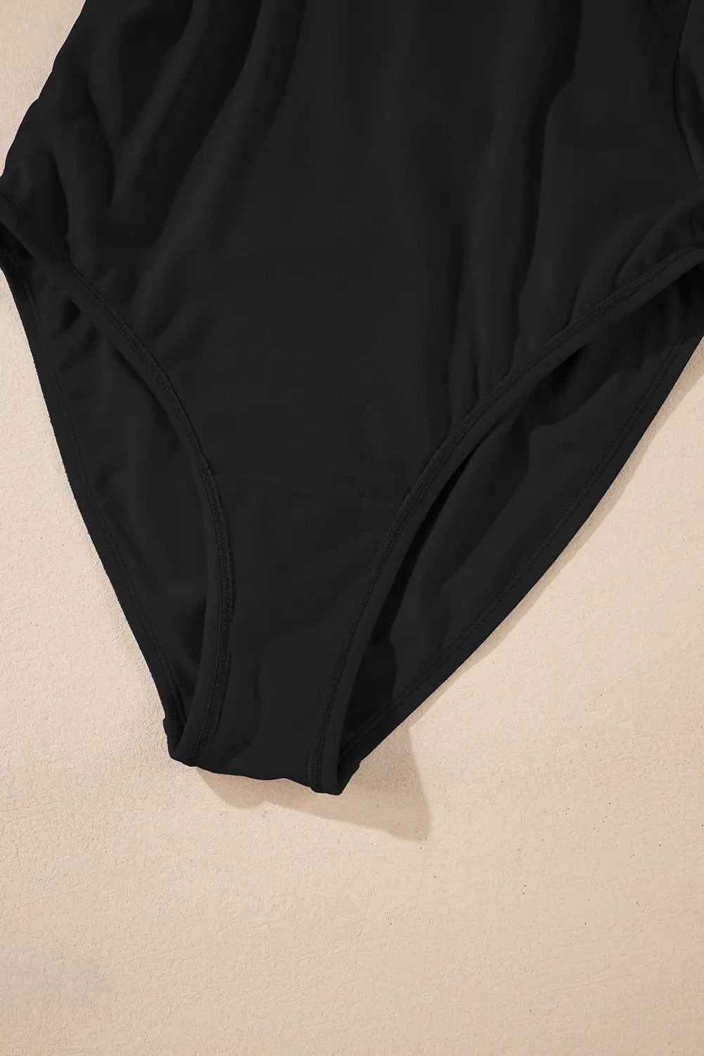 Black swimsuit on a beige background