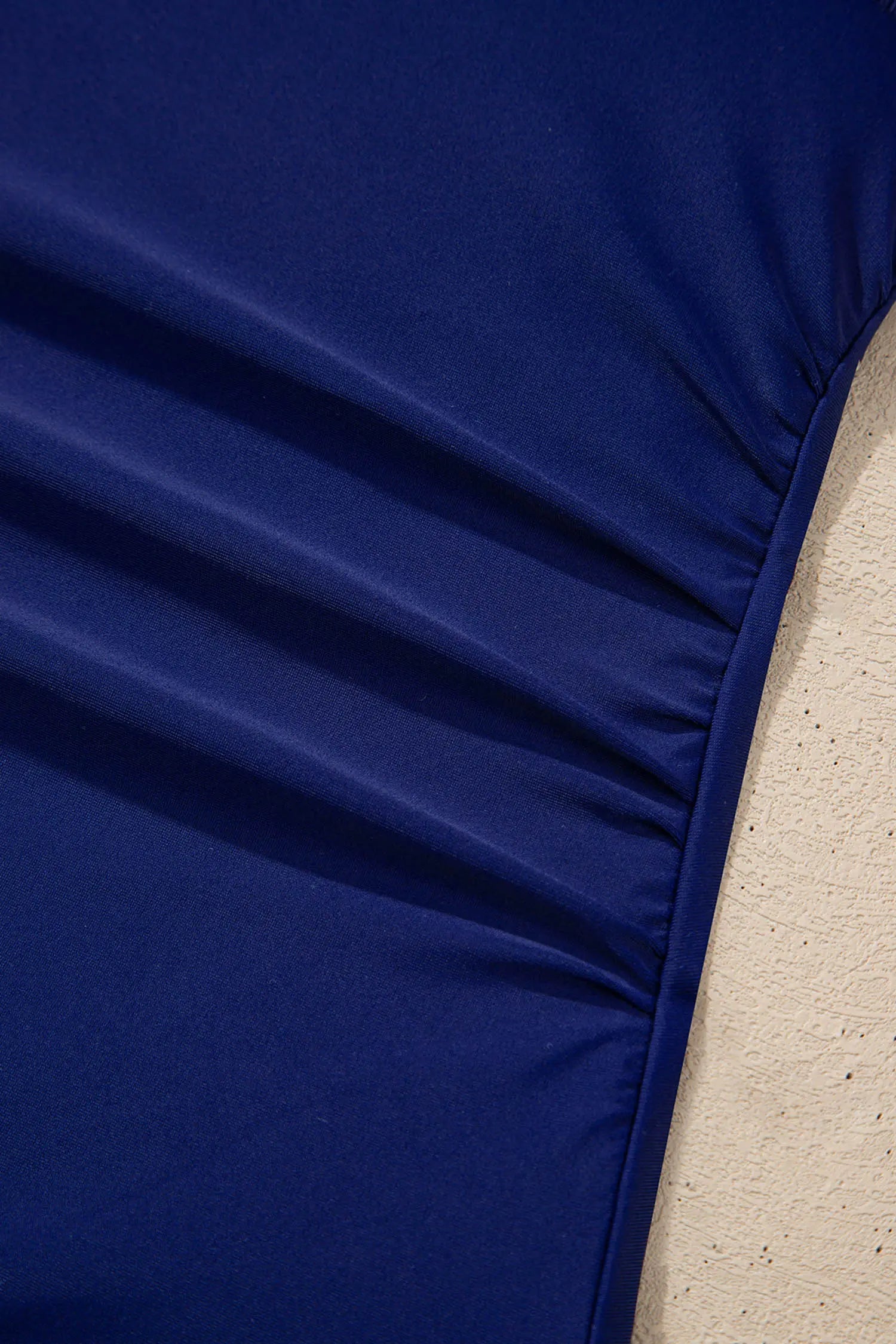 Close-up of a blue fitted sheet on a bed with a beige background