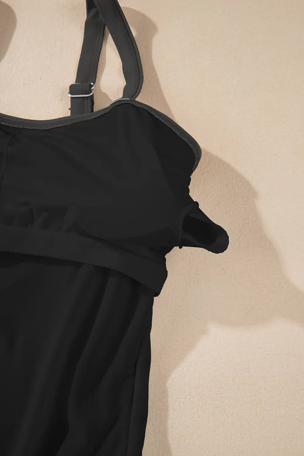 Black dress with straps on a beige background