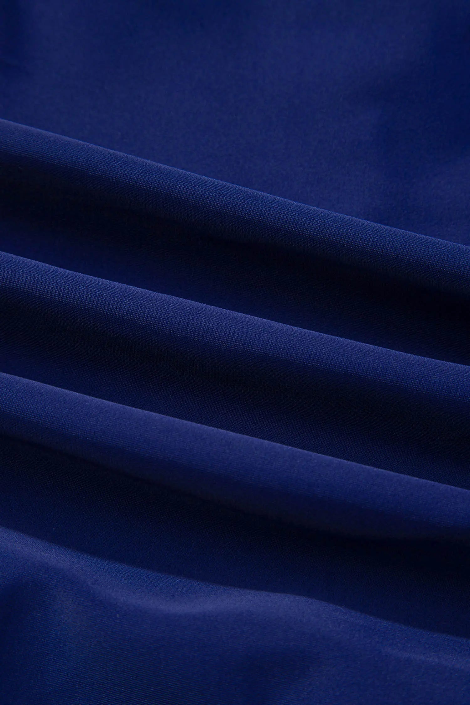A close-up of draped royal blue fabric with soft folds and a smooth texture.