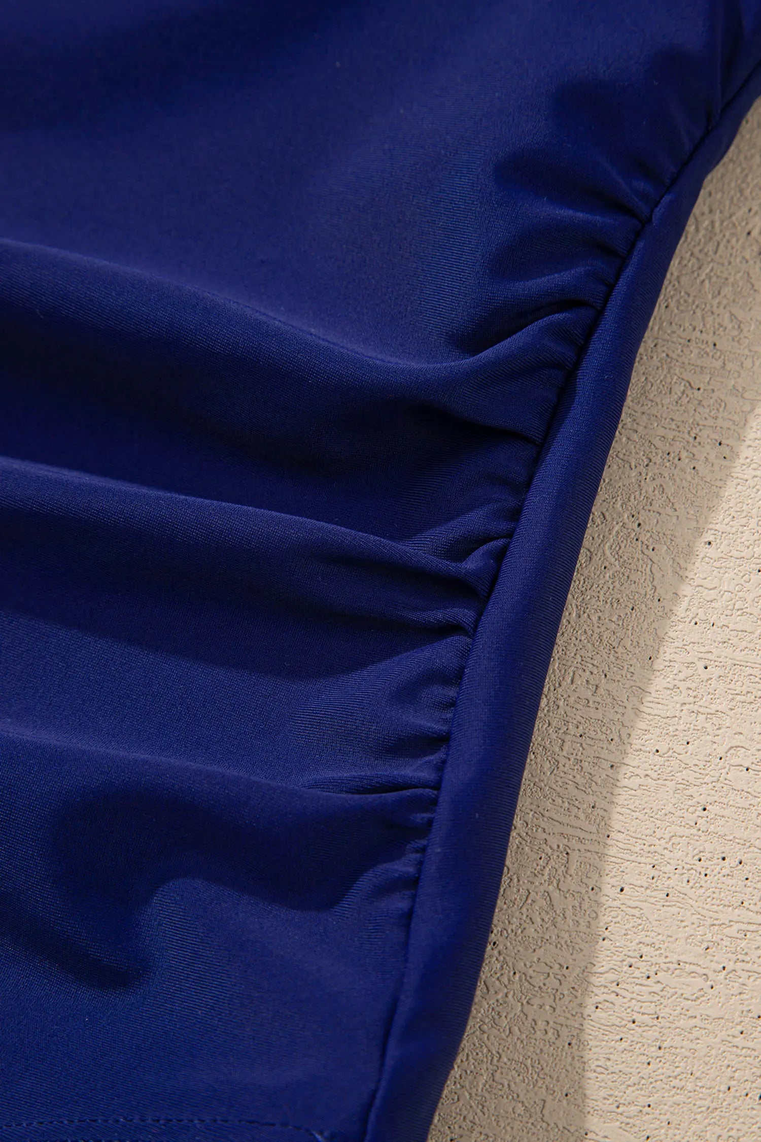 Close-up of a blue fabric surface on a textured beige background