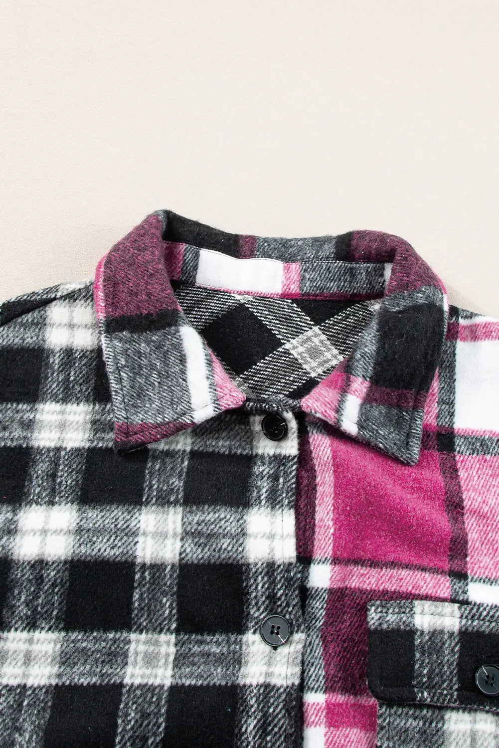 Close-up of a plaid button-up shirt collar and upper chest in a mixed pattern of black, white, gray, and magenta pink.