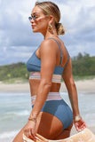 Woman in a blue bikini standing on a beach with ocean and sky in the background