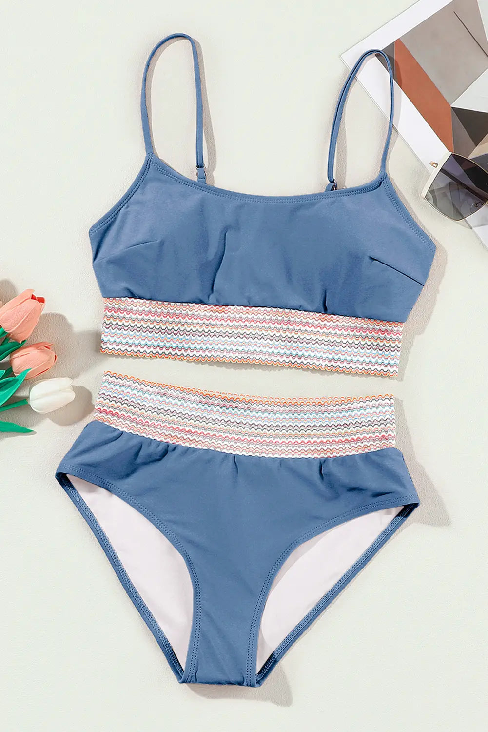 Blue two-piece swimsuit with striped design on a light background
