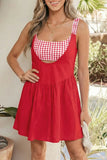 Woman wearing a red dress with a white checkered top, standing outdoors.