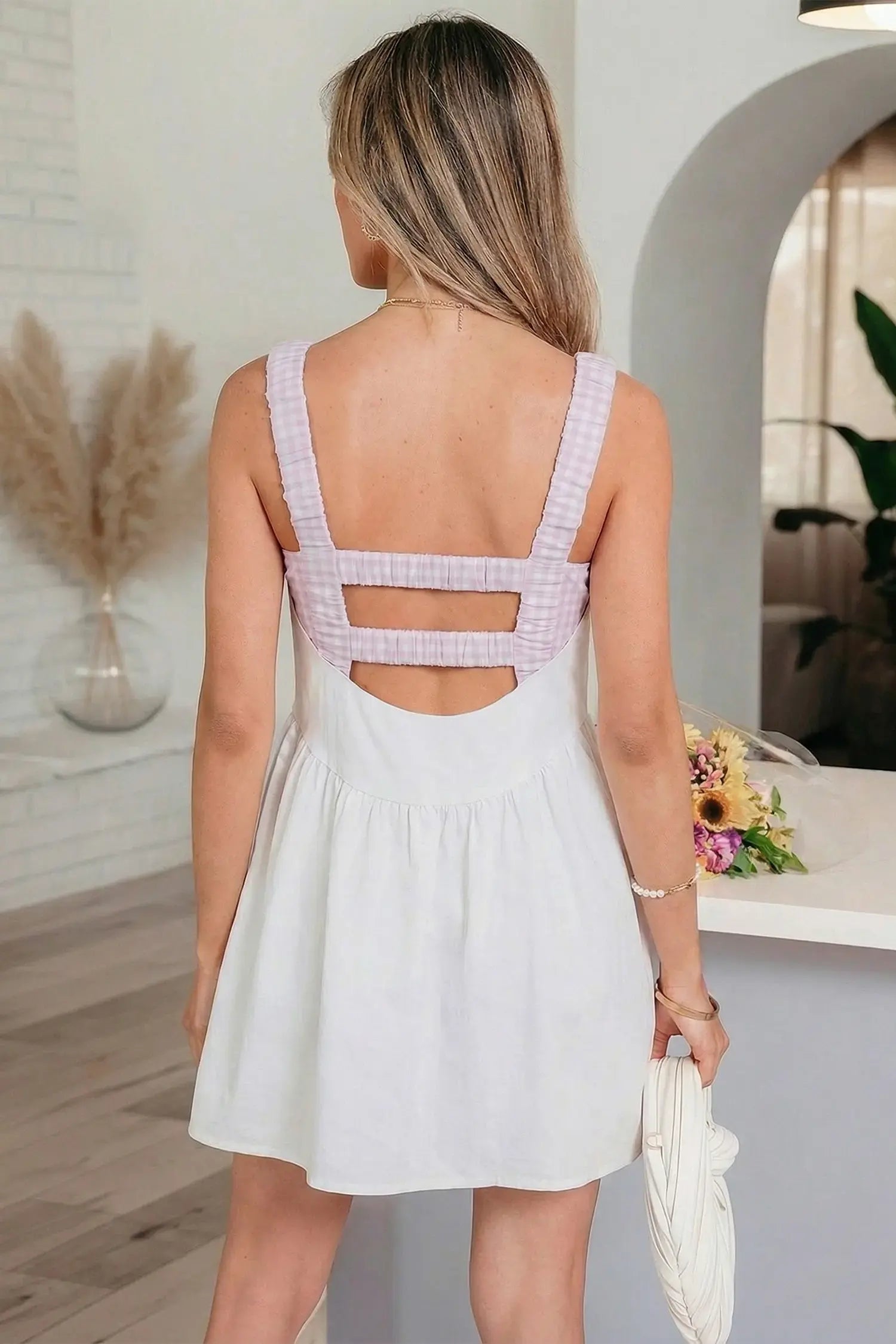 Woman wearing a white dress with a checkered back design in an indoor setting.