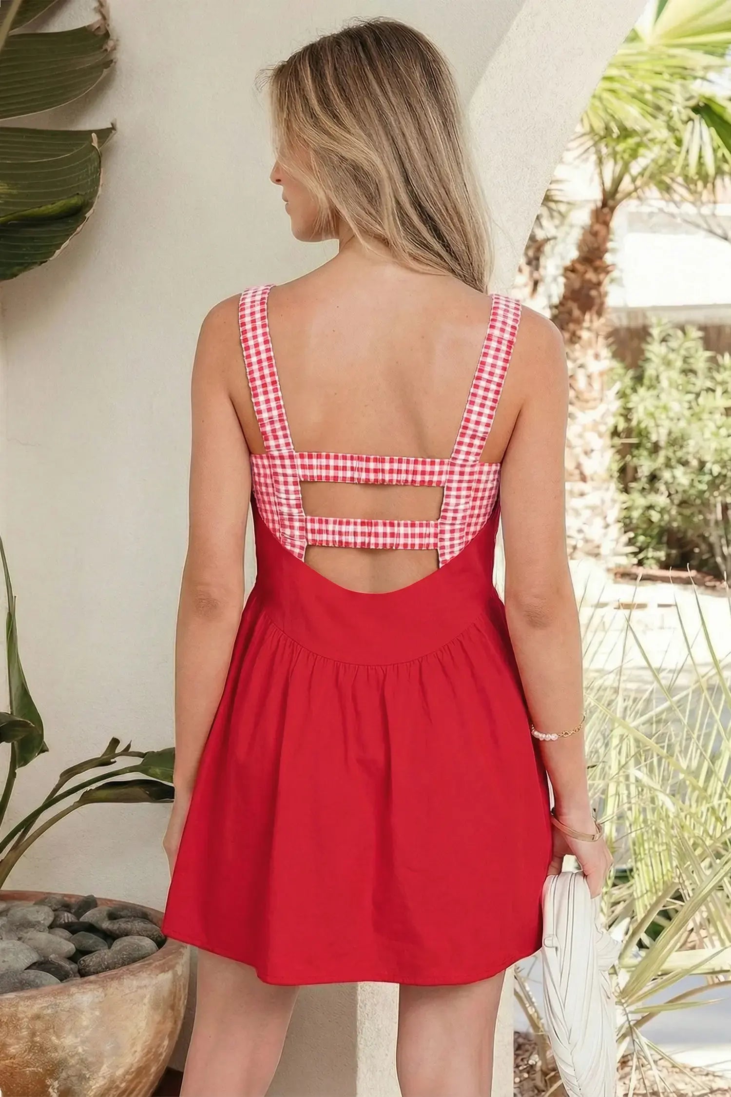 Woman wearing a red dress with a checkered back in an outdoor setting