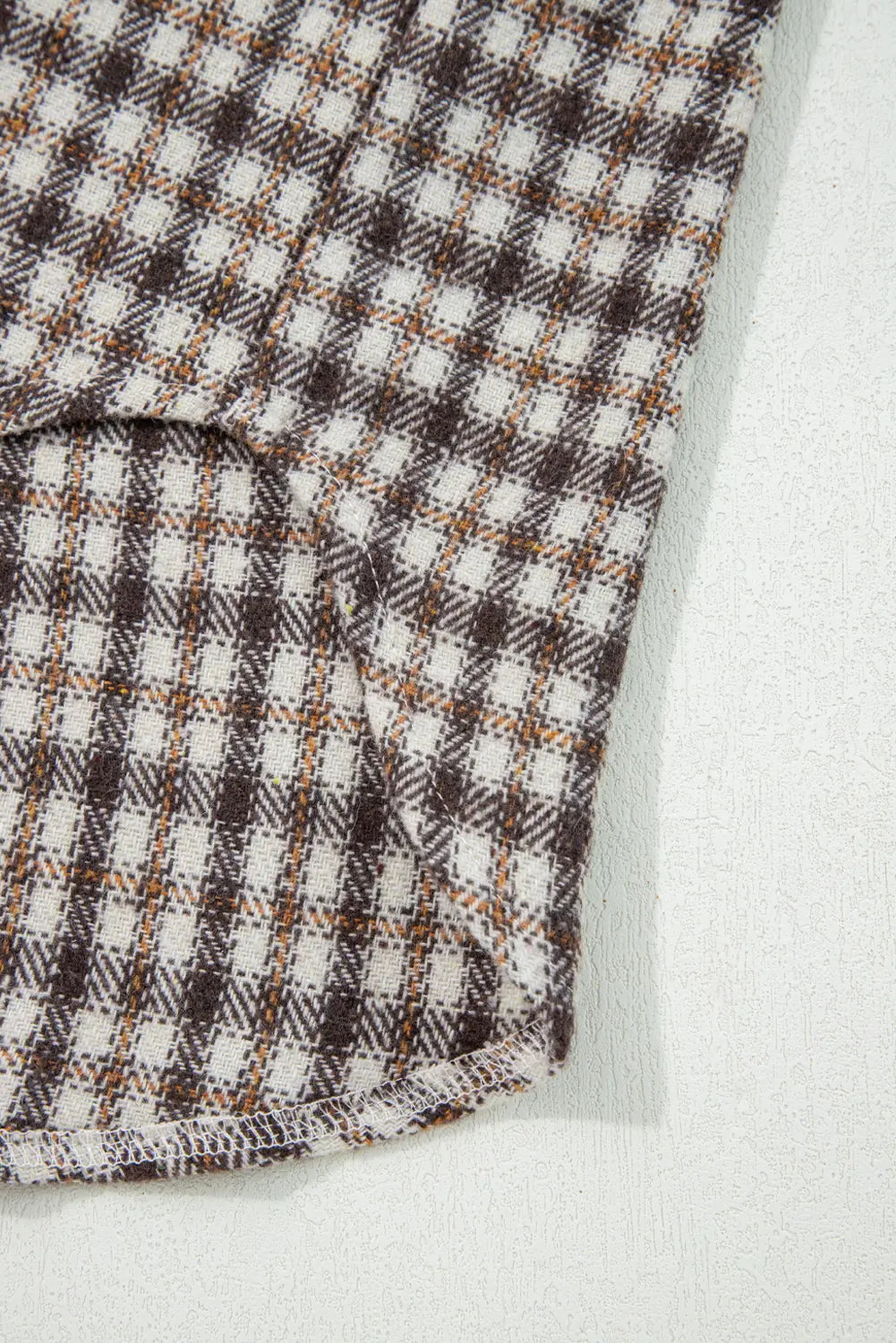 Close-up of checkered fabric with brown and white pattern on a light background