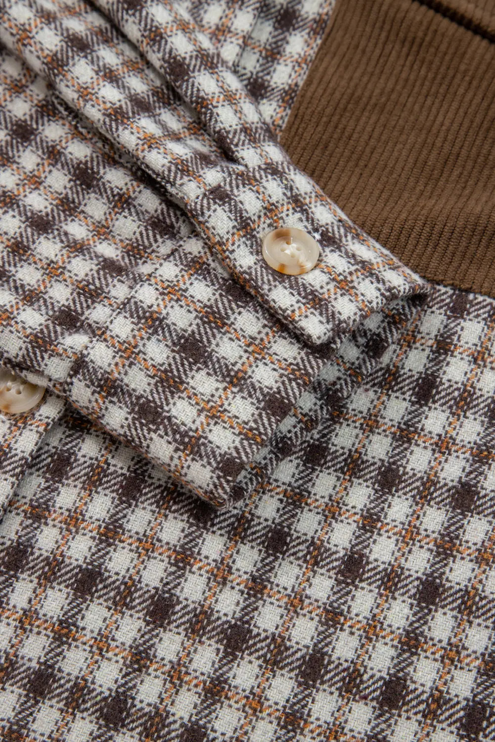 Close-up of a checkered fabric with a button, featuring brown, white, and beige colors.