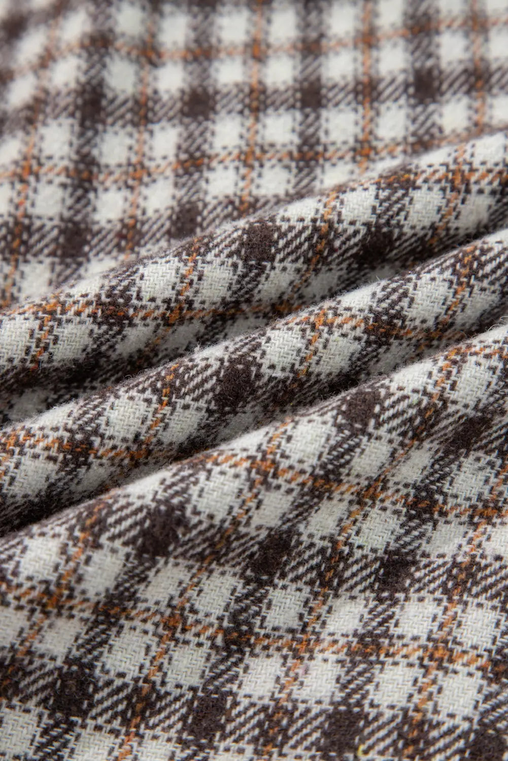 Close-up of plaid fabric with brown, white, and orange colors.