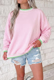 Woman in light pink sweatshirt with mint-green striped trim and distressed denim shorts.