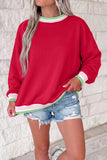 Woman in red sweatshirt with green-white striped trim and distressed denim shorts.