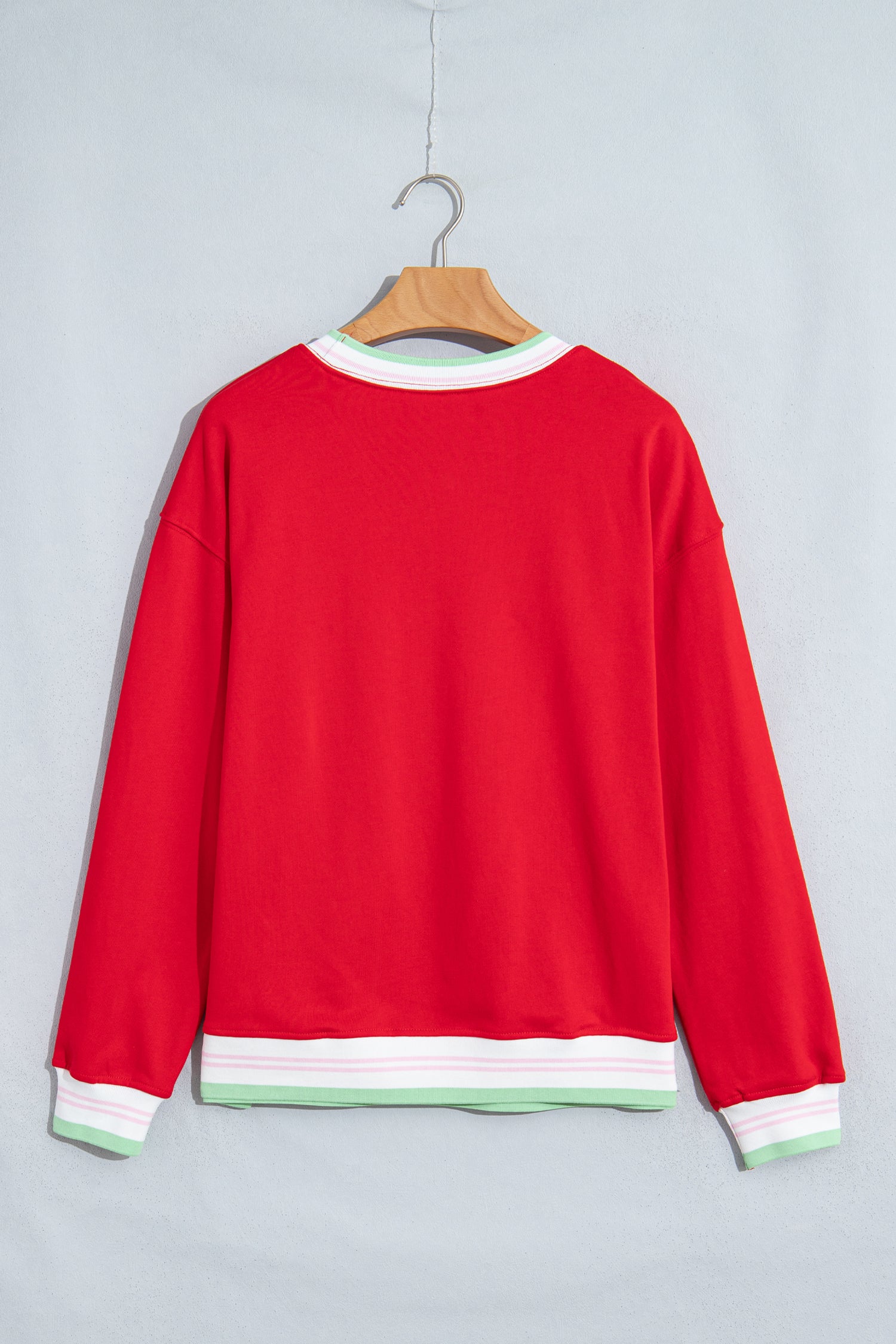 A bright red crewneck sweatshirt hanging on a wooden hanger against